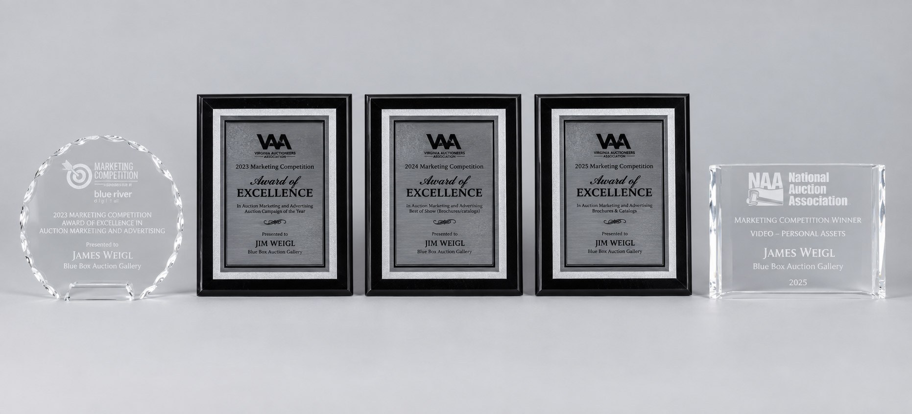 Five marketing awards in a row: a 2023 National Auction Association Marketing Competition crystal, three Virginia Auctioneers Association Award of Excellence plaques from 2023, 2024, and 2025, and a 2025 National Auction Association Marketing Competition Winner crystal